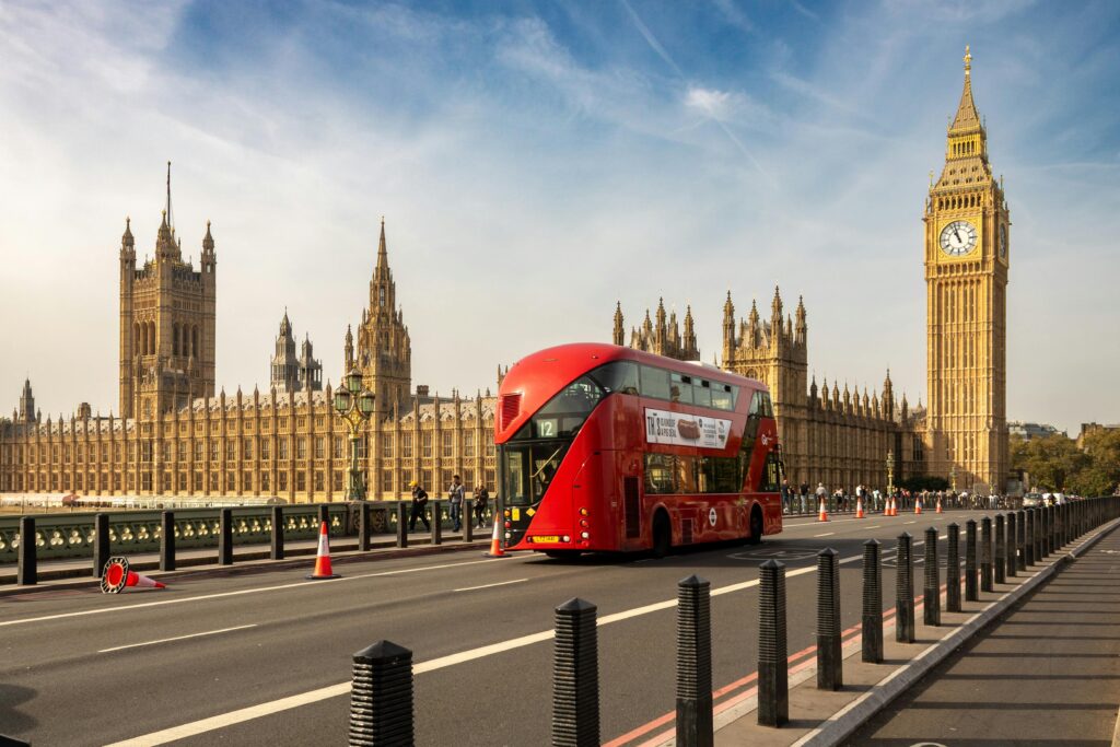 Classic red double-decker bus passing Elizabeth Tower in London. Perfect for travel and cityscape themes.